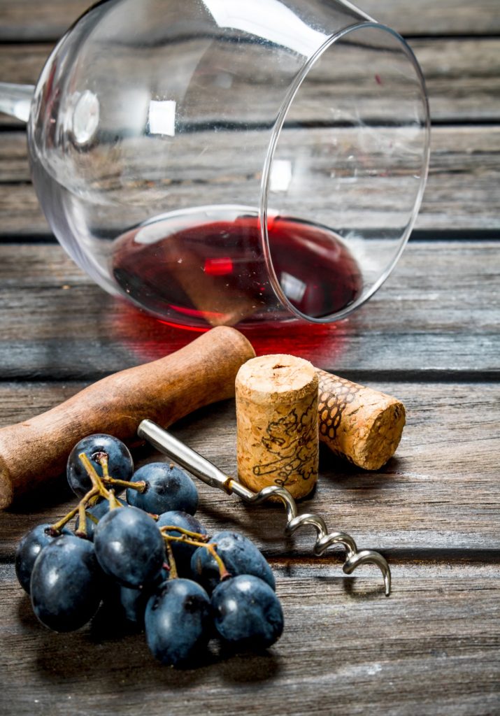 Wine background. A glass of red wine with a corkscrew and a vine.